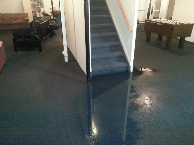 Water covering the carpet of a finished Framingham basement at the foot of the stairs